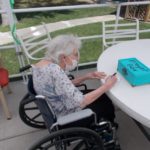 elderly women in wheel chair praying at a blue prayer box
